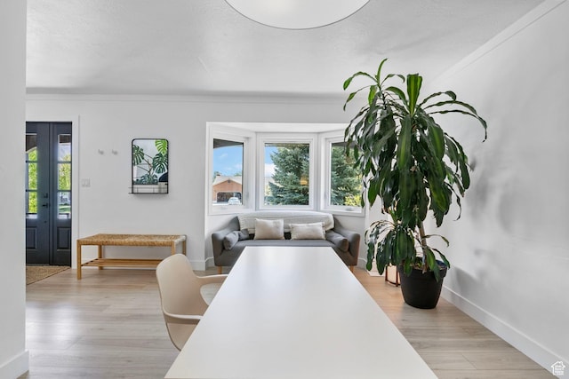dining room with light wood-style floors, crown molding, and baseboards