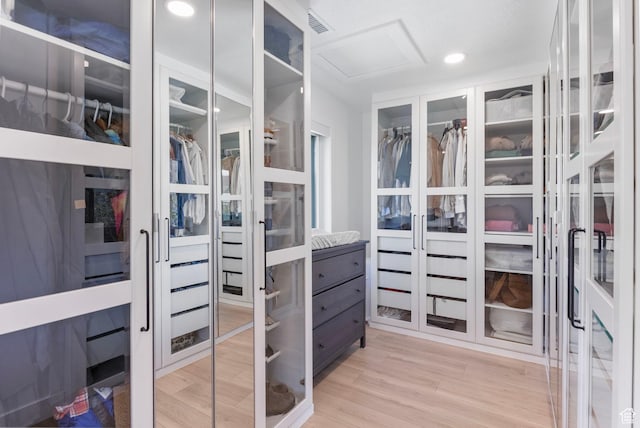 walk in closet featuring attic access and light wood finished floors