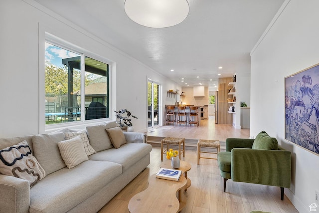 living area with crown molding, recessed lighting, light wood-style flooring, and baseboards