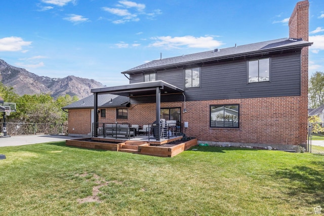 rear view of property with fence, a chimney, a lawn, and a mountain view