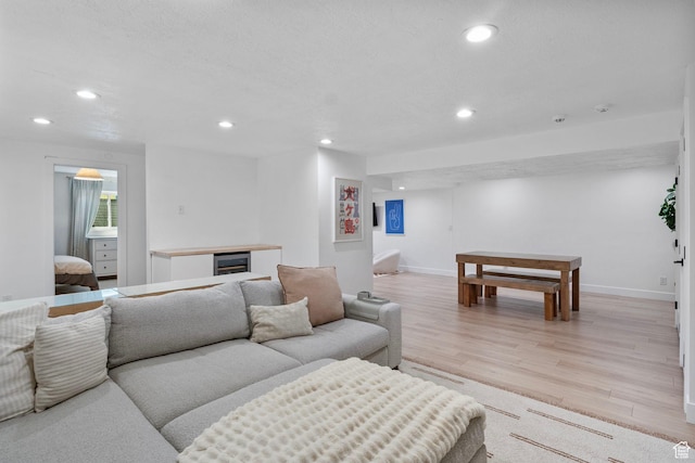 living area featuring beverage cooler, recessed lighting, light wood-style flooring, and baseboards