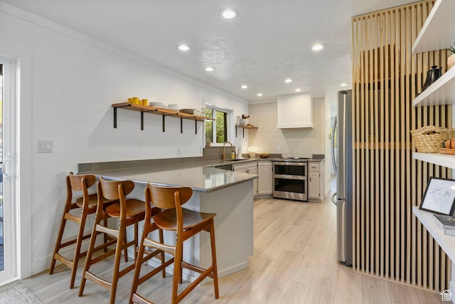 kitchen with tasteful backsplash, open shelves, appliances with stainless steel finishes, a sink, and a peninsula