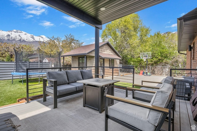view of patio featuring fence, a mountain view, an outdoor hangout area, and a trampoline