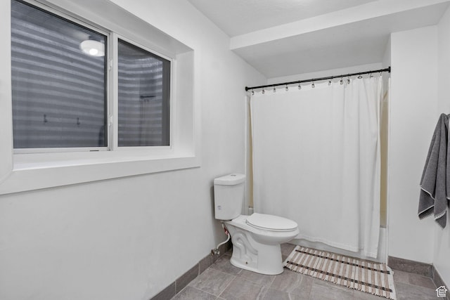 full bath featuring shower / bath combo, toilet, and baseboards