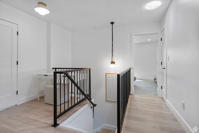 hallway featuring light wood finished floors, an upstairs landing, and baseboards