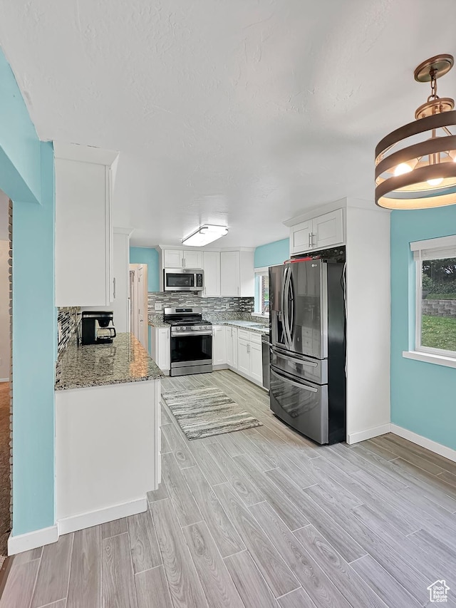 886 E Hillcrest Dr, Springville, UT 84663 - kitchen featuring light stone countertops, light wood-style floors, baseboards, white cabinets, and appliances with stainless steel finishes