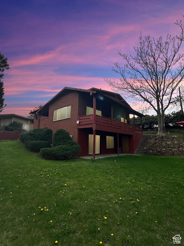 886 E Hillcrest Dr, Springville, UT 84663 - back of house at dusk with a patio, a wooden deck, a yard, and brick siding