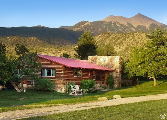 view of front of house with metal roof, a front yard, and a mountain view