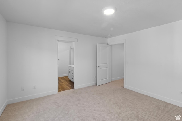 unfurnished bedroom with carpet, connected bathroom, and baseboards