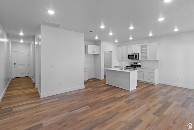 kitchen featuring a sink, open shelves, baseboards, white cabinets, and appliances with stainless steel finishes