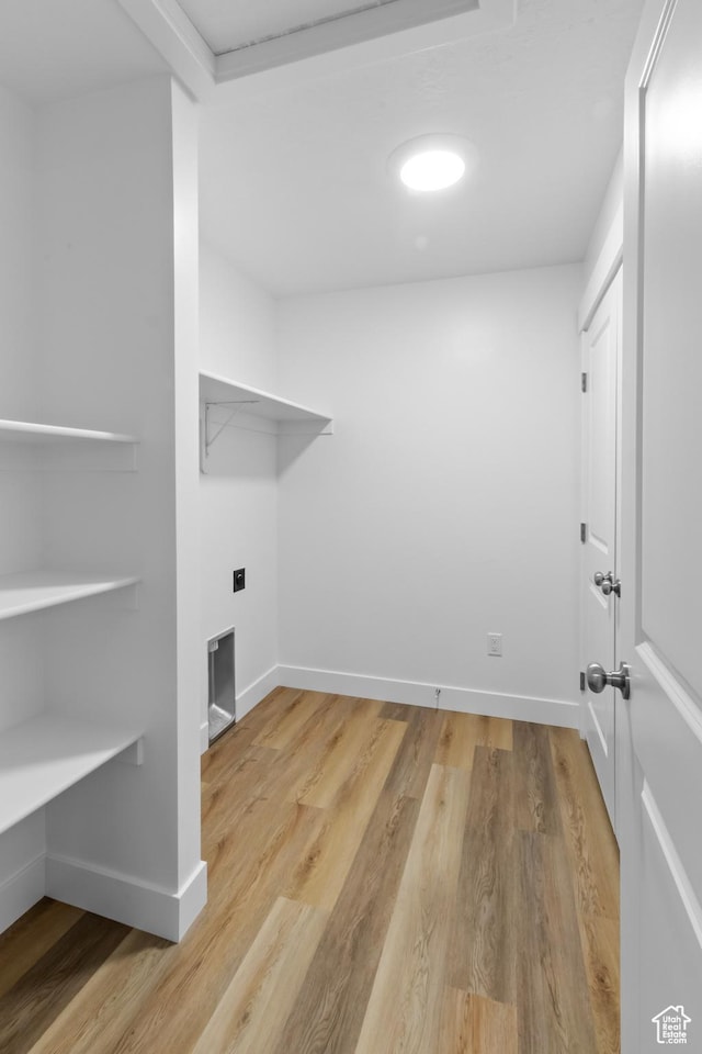 laundry area featuring wood finished floors, laundry area, and baseboards