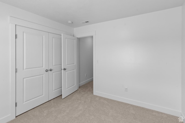 unfurnished bedroom featuring light colored carpet, visible vents, a closet, and baseboards