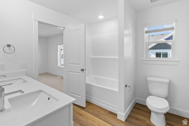 full bathroom featuring a wealth of natural light, wood finished floors, toilet, and a sink