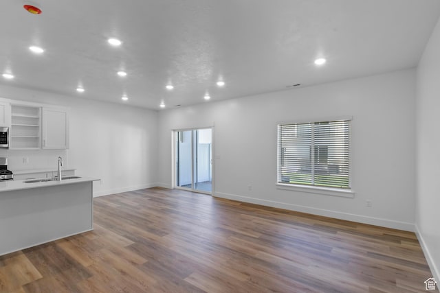 unfurnished living room with recessed lighting, a sink, wood finished floors, and a healthy amount of sunlight
