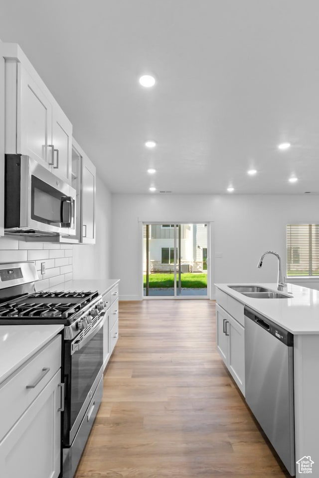 kitchen with recessed lighting, a sink, tasteful backsplash, light countertops, and appliances with stainless steel finishes