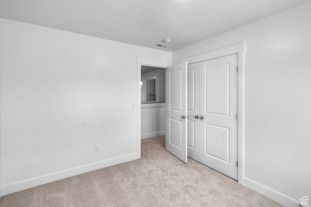 unfurnished bedroom featuring light colored carpet, visible vents, a closet, and baseboards