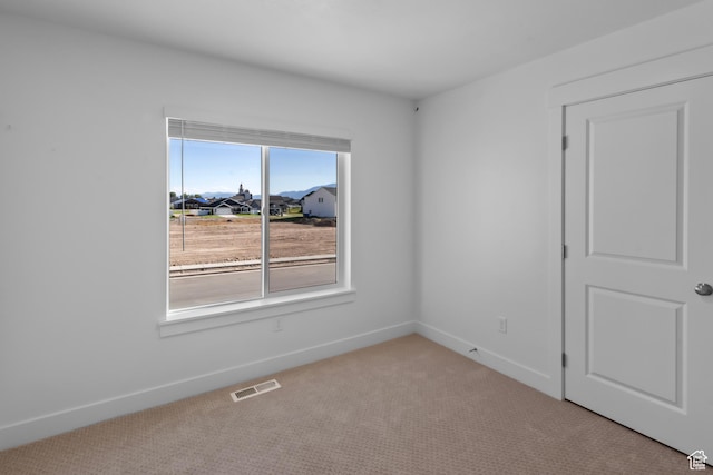 spare room featuring visible vents, carpet, and baseboards