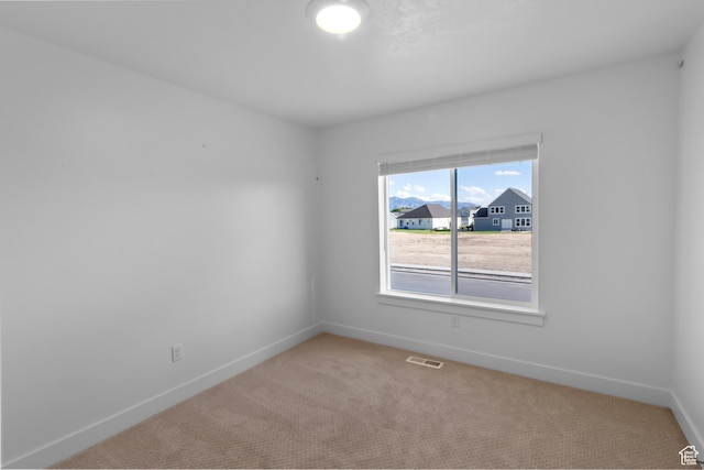 spare room featuring baseboards, visible vents, and light carpet