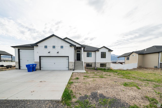 9568 N 5600 W, Elwood, UT 84337 - view of front facade featuring board and batten siding, fence, stone siding, concrete driveway, and an attached garage