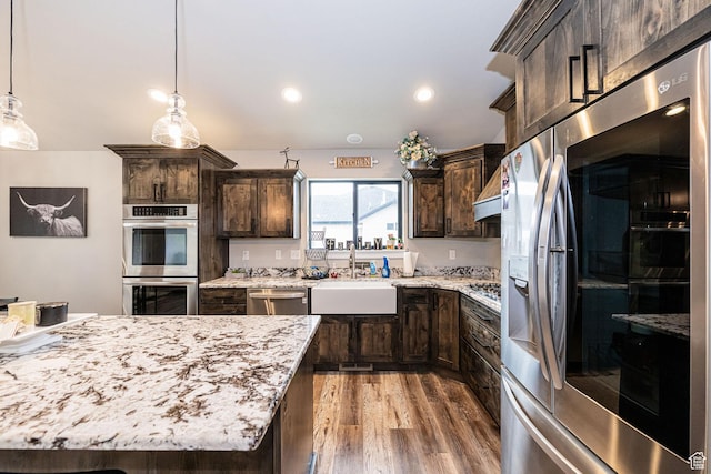 9568 N 5600 W, Elwood, UT 84337 - kitchen with light stone countertops, a sink, stainless steel appliances, light wood-style floors, and dark brown cabinetry