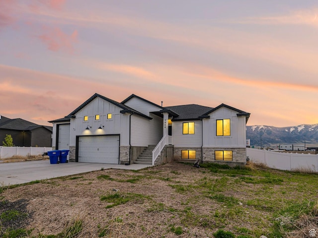 tri-level home with fence, board and batten siding, concrete driveway, and stone siding