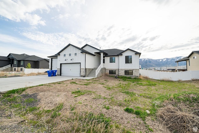 9568 N 5600 W, Elwood, UT 84337 - view of front of home featuring board and batten siding, concrete driveway, a mountain view, fence, and a garage