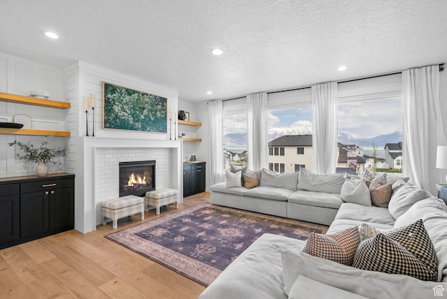 2862 S Preening Way, Saratoga Springs, UT 84045 - living room with a brick fireplace, recessed lighting, a textured ceiling, and light wood-style flooring