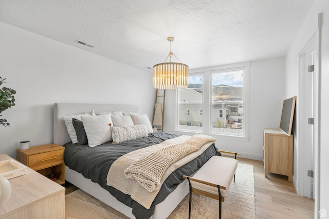 2862 S Preening Way, Saratoga Springs, UT 84045 - bedroom featuring visible vents, light wood-type flooring, a textured ceiling, and an inviting chandelier