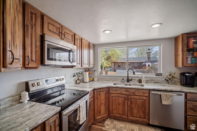 537 E 650 N, Roosevelt, UT 84066 - kitchen featuring light stone counters, brown cabinetry, appliances with stainless steel finishes, a sink, and a textured ceiling