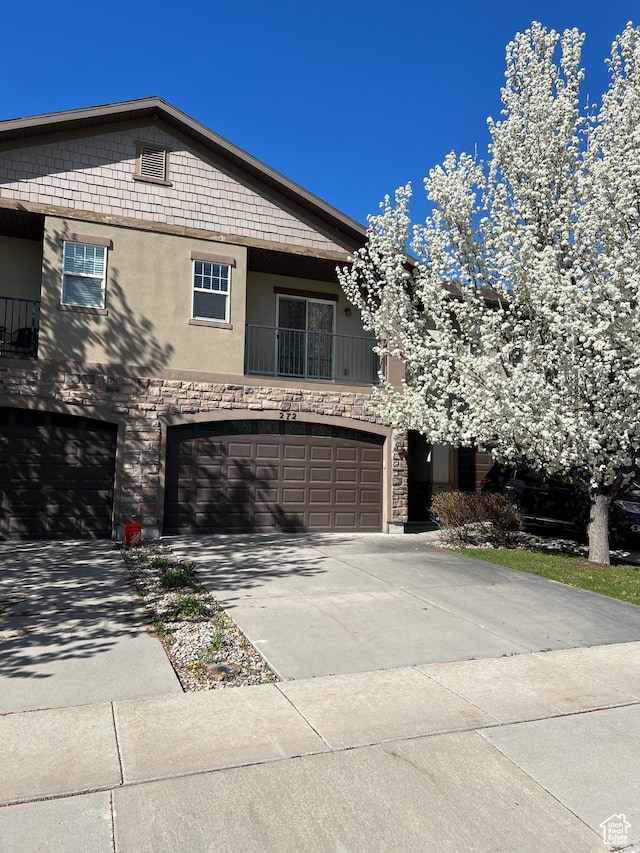 272 W 680 N, Centerville, UT 84014 - view of front of property featuring driveway, a balcony, stone siding, an attached garage, and stucco siding