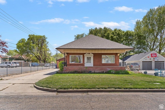 bungalow-style house featuring fence, roof with shingles, a front lawn, and brick siding