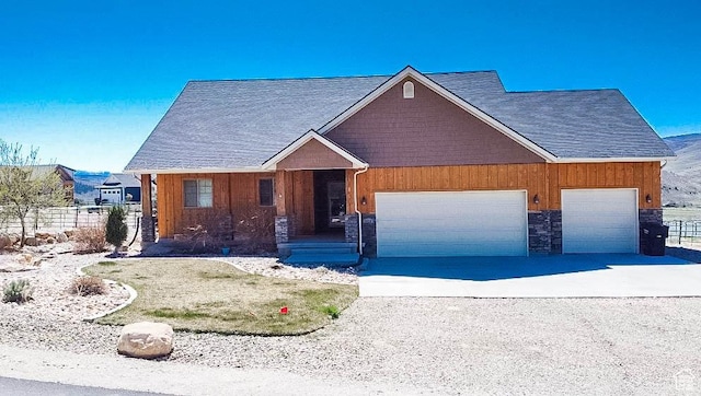 view of front of house with fence, concrete driveway, stone siding, and a garage