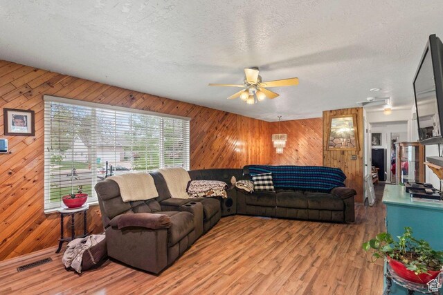 3168 W 1300 N, Clinton, UT 84015 - living area featuring a textured ceiling, ceiling fan, wood walls, and light wood-style floors