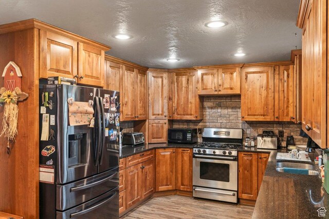 3168 W 1300 N, Clinton, UT 84015 - kitchen featuring tasteful backsplash, a sink, black appliances, light wood finished floors, and brown cabinetry