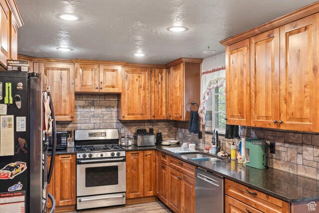 3168 W 1300 N, Clinton, UT 84015 - kitchen featuring dark stone counters, a sink, appliances with stainless steel finishes, and decorative backsplash