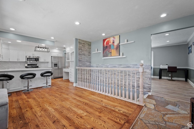 living area featuring ornamental molding, light wood finished floors, recessed lighting, and baseboards