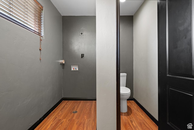 bathroom featuring baseboards, wood finished floors, and toilet