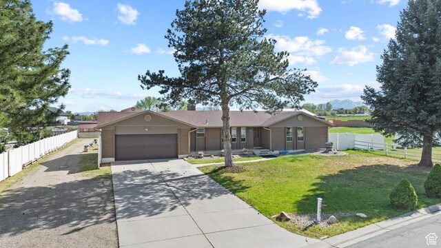 ranch-style home with a fenced backyard, brick siding, a front yard, concrete driveway, and an attached garage