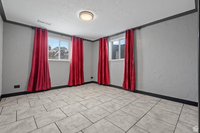 empty room with visible vents, a wealth of natural light, a textured ceiling, and a textured wall