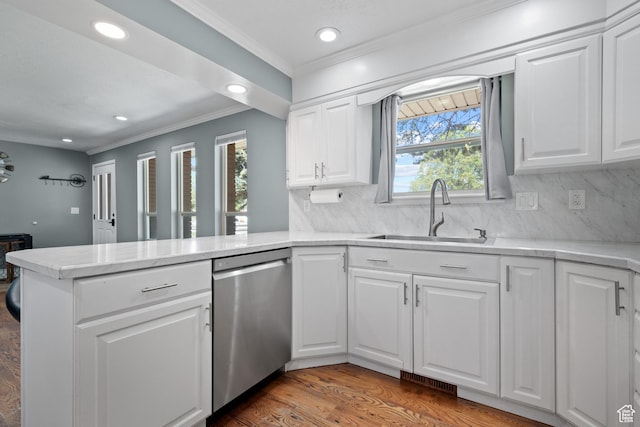 kitchen with a sink, decorative backsplash, ornamental molding, a peninsula, and stainless steel dishwasher