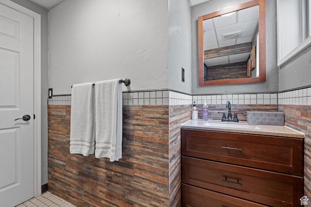bathroom featuring a wainscoted wall, visible vents, vanity, and tile walls