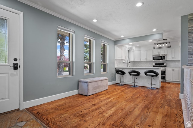 kitchen with stainless steel appliances, crown molding, white cabinets, and baseboards