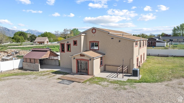 exterior space featuring a mountain view, fence, stucco siding, and central air condition unit