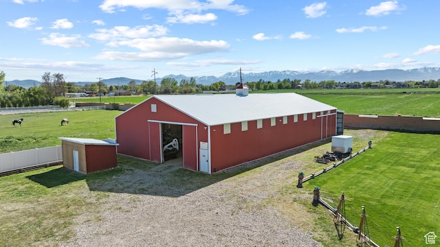 view of pole building with a mountain view, a rural view, a lawn, and fence