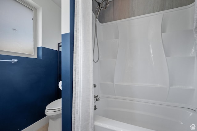 bathroom featuring toilet, shower / bath combo, and baseboards