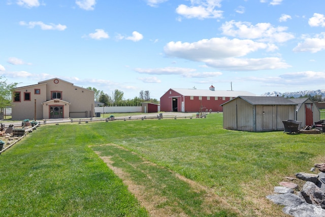 view of yard with an outbuilding, a storage unit, and fence