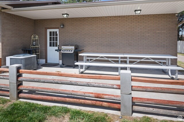view of exterior entry featuring central AC unit and brick siding