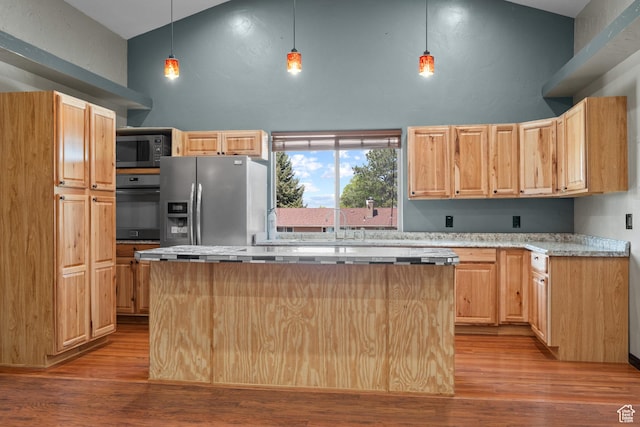 kitchen with light brown cabinetry, high vaulted ceiling, appliances with stainless steel finishes, and a kitchen island
