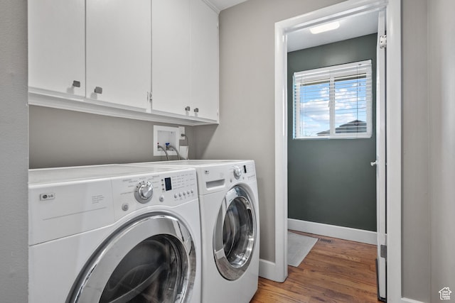 washroom featuring cabinet space, separate washer and dryer, light wood finished floors, and baseboards