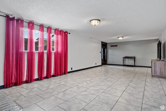 empty room featuring a textured ceiling and baseboards